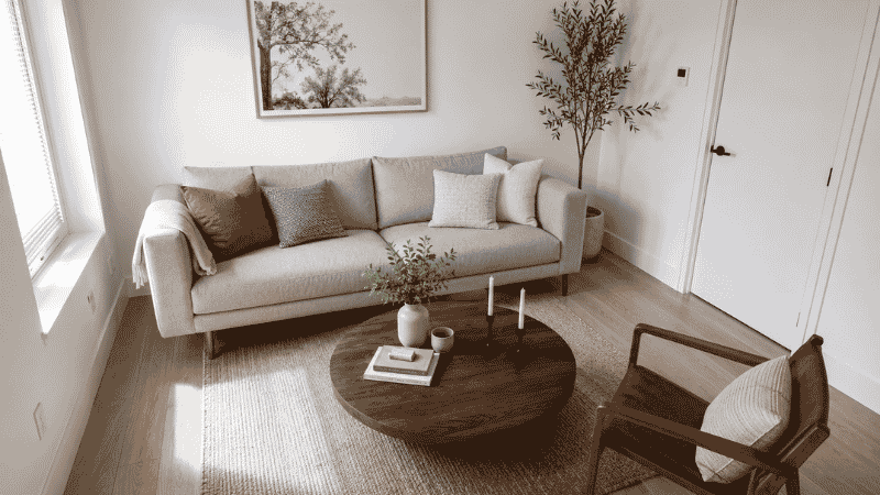 A compact living room with a floating sofa, round coffee table, and open walkway showing an efficient small space layout