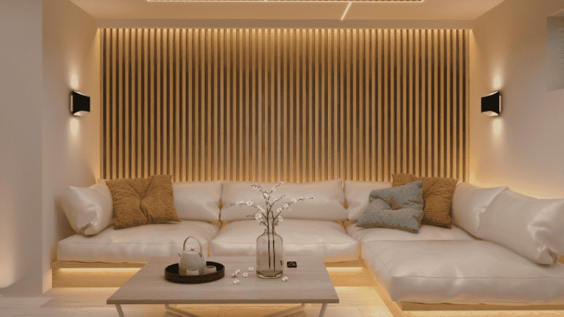 A mid-century modern sofa with a finished walnut back used as a structural room divider to separate the sleeping and living zones in a studio apartment.